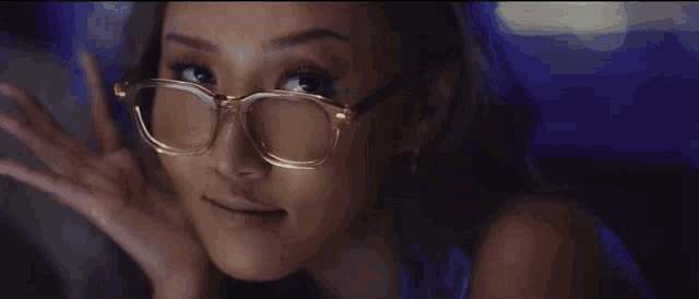 a close up of a woman wearing glasses with her hand on her face