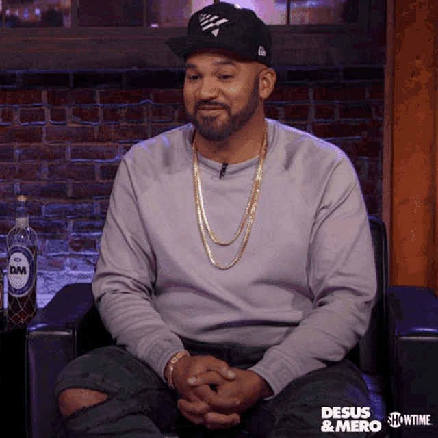 a man sitting in a chair wearing a sweater that says desus & mero