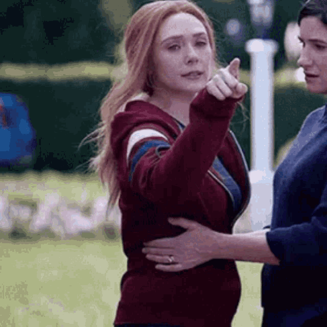 a woman is hugging another woman and pointing at something while another woman holds her waist .