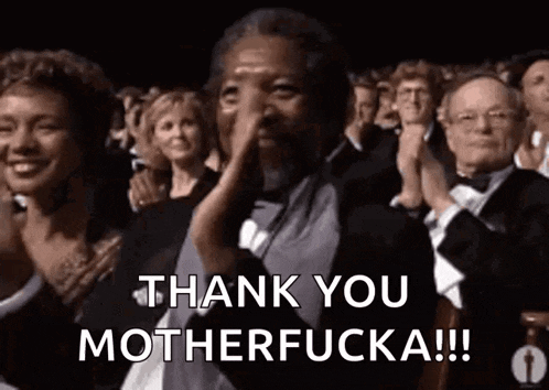 a man in a tuxedo is applauding in front of a crowd .