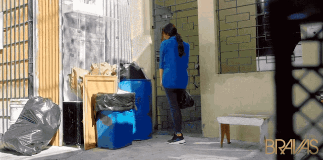a woman in a blue jacket is standing in front of a building with bravas written on it