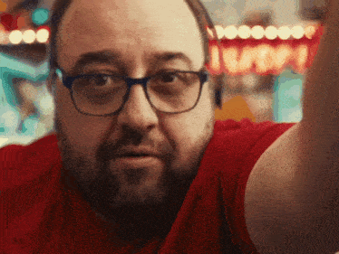 a man wearing glasses and a red shirt takes a picture of himself