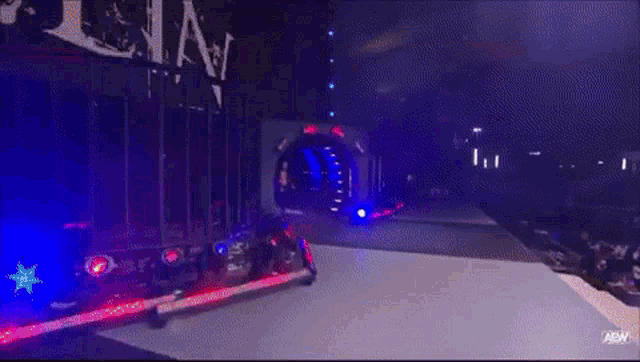 a wrestler named darby allin is standing in front of a wall of lights .