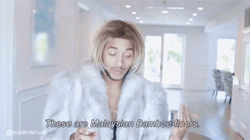 a man in a fur coat is sitting at a table and says these are malaysian bamboo floors