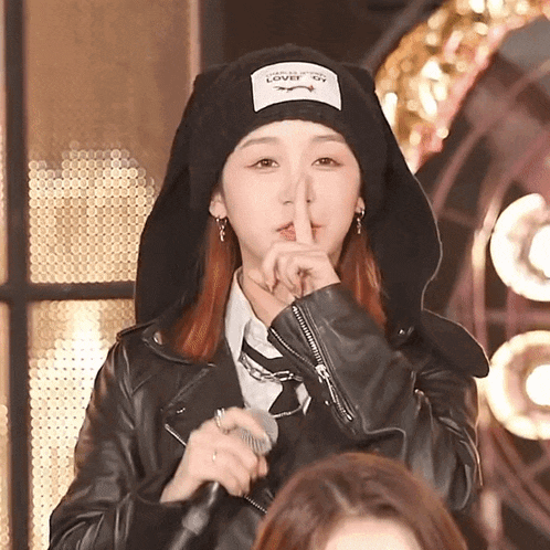 a woman wearing a hat that says lover on it holds her finger to her lips