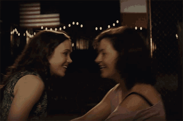 two women are hugging each other in a dark room