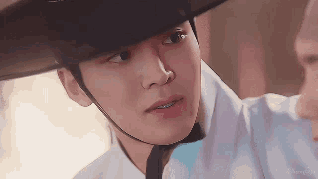 a close up of a person wearing a hat and a white shirt .