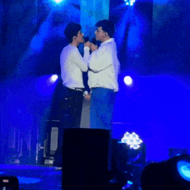 a man singing into a microphone while another man stands behind him