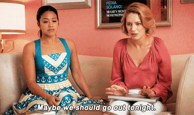 two women are sitting on a couch and one says maybe we should go out tonight
