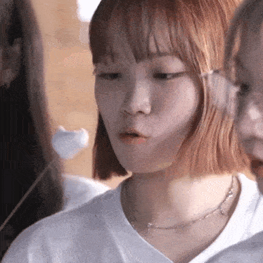 a close up of a woman 's face with a marshmallow in her mouth