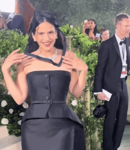 a woman in a black dress is smiling while holding a black tie