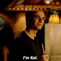 a man in a black shirt is holding a cigarette and says i 'm kol .