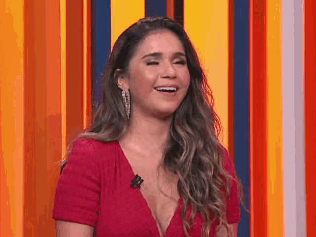 a woman in a red dress is laughing in front of a striped background