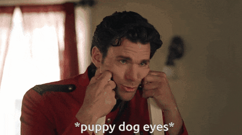 a man in a red jacket adjusts his earring with the words puppy dog eyes below him