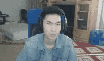 a man wearing headphones and a denim shirt is making a funny face in a living room .