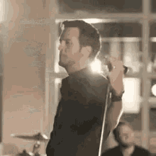 a man is singing into a microphone while playing a guitar in a band .