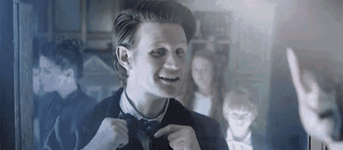 a man is adjusting his bow tie in front of a mirror .