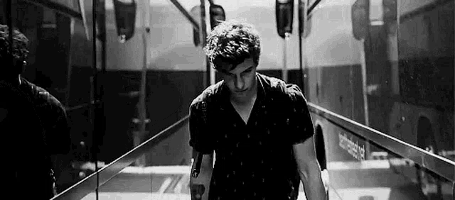 a black and white photo of a man walking down a set of stairs .