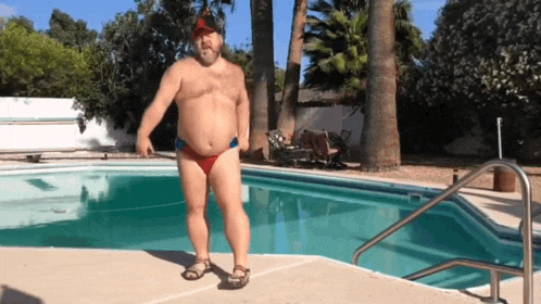 a shirtless man is standing in front of a pool