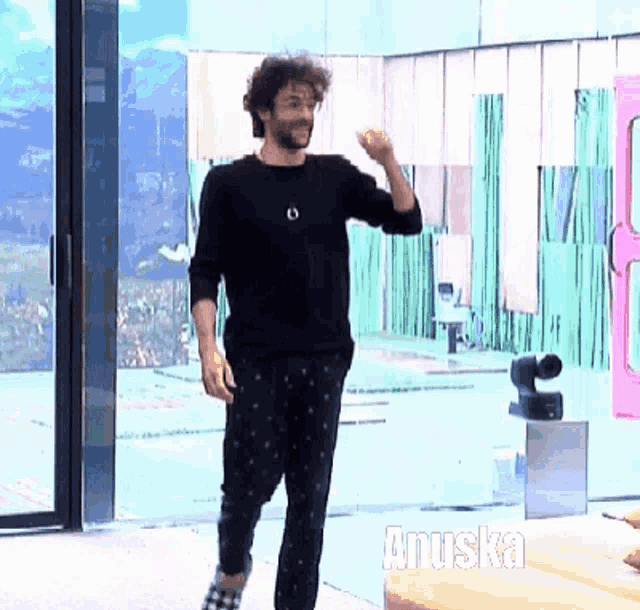a man in a black shirt and black pants is standing in front of a glass door with the word anuska written on it
