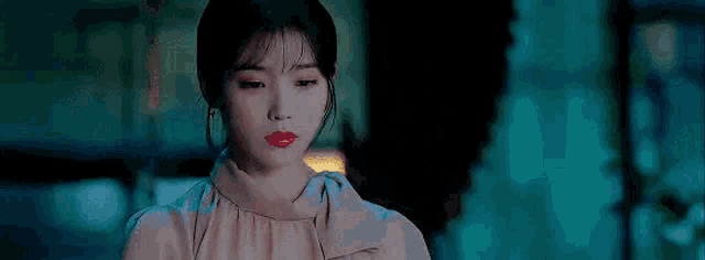 a woman in a pink dress is standing in a dark room .