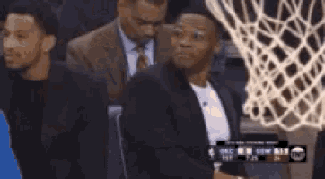 a group of men are standing around a basketball net .