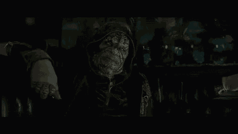 a man in a hooded jacket is standing in the dark in a dark room .