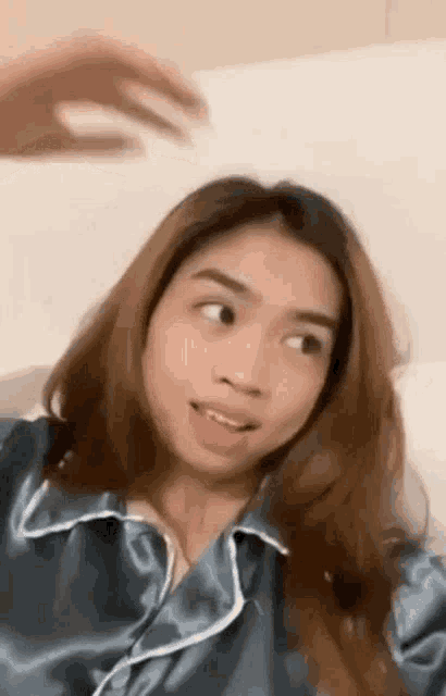 a young woman is sitting on a bed making a funny face while wearing pajamas .