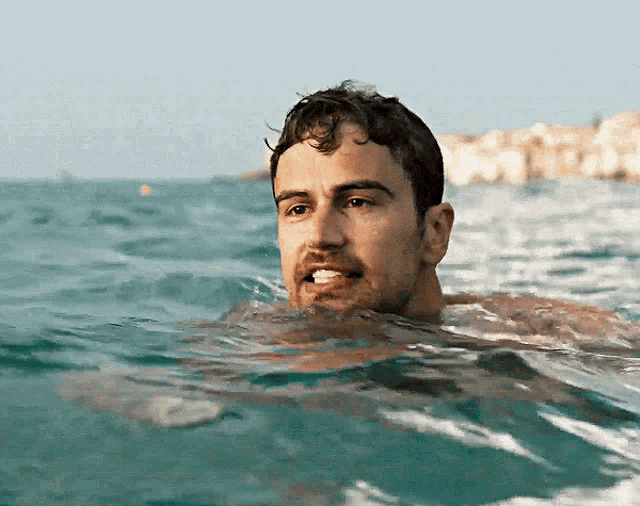 a man is swimming in the ocean and looking at the camera