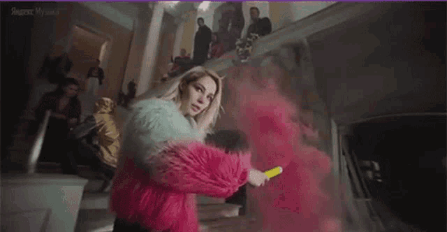 a woman in a fur coat is holding a pink smoke bomb in a room .