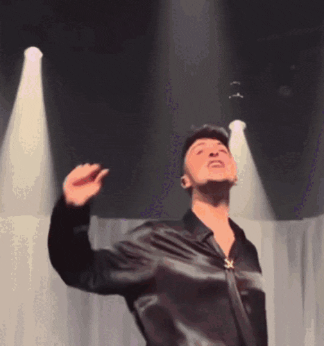 a man in a black shirt and hat is dancing on stage