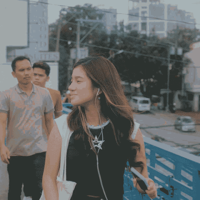 a woman wearing headphones is walking down a street in front of a building that says i wood suites