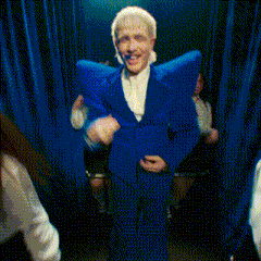 a man in a blue suit is dancing with a group of women in school uniforms .