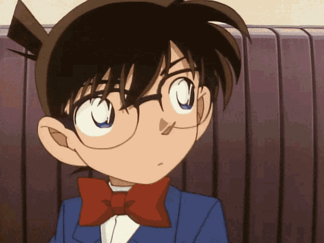 a boy with glasses and a bow tie looks at the camera
