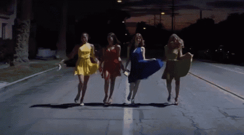 a group of women in dresses are walking down a street