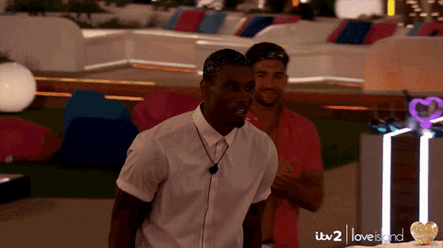two men are standing in front of a sign that says itv 2 love island