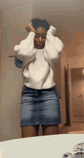 a woman wearing a white sweater and a blue skirt