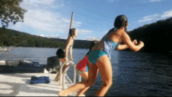 a woman in a blue bikini is jumping into a body of water