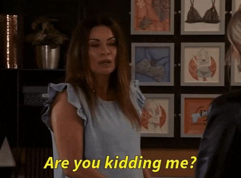 a woman says are you kidding me while standing in front of a wall of pictures