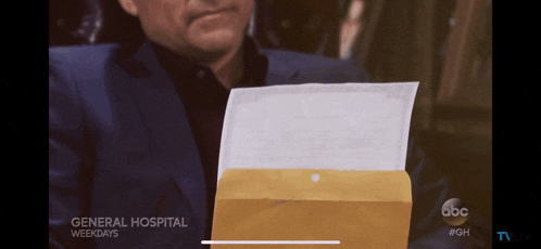 a man in a suit is holding an envelope that says general hospital