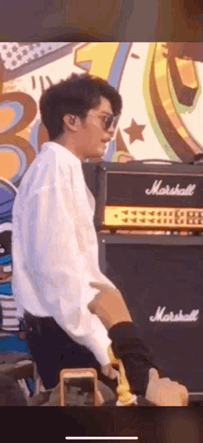 a man is standing in front of a marshall amplifier .