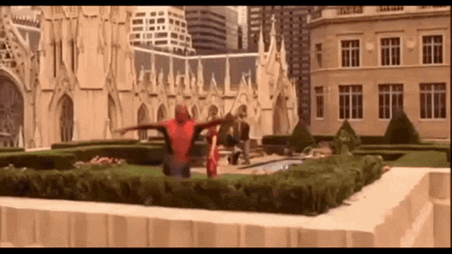 a man in a spiderman costume is flying through the air in a garden .