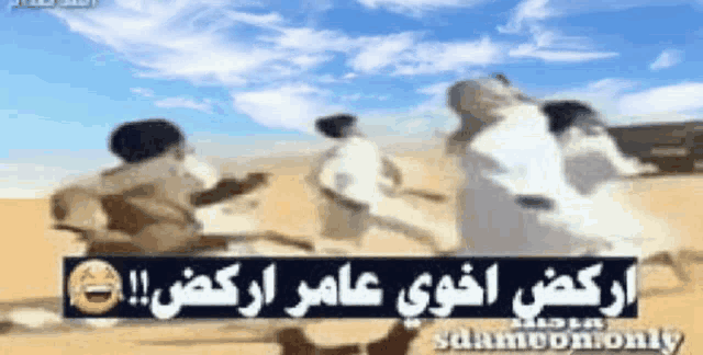 a group of men are standing in the desert with arabic writing behind them