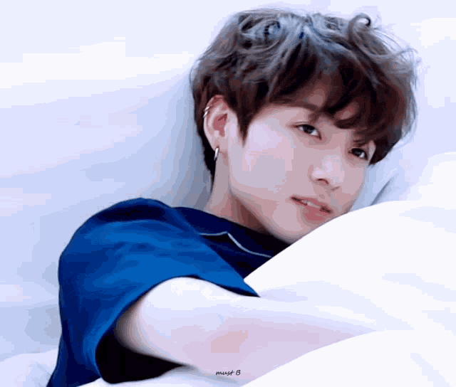a young boy in a blue shirt is laying on a bed with a pillow .