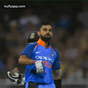 a cricket player wearing a blue jersey with the word oppo india on it