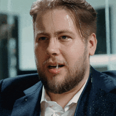 a man with a beard and a blue suit has water running down his face