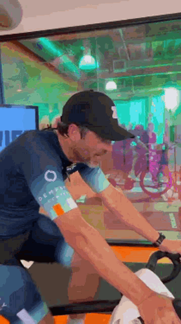 a man wearing a hat is riding an exercise bike in a gym .