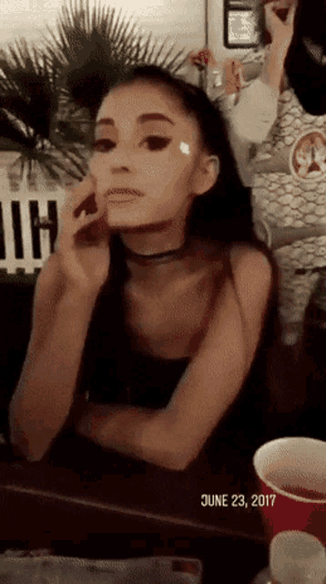 a woman is sitting at a table smoking a cigarette and the date is june 23, 2017