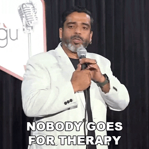a man speaking into a microphone with the words nobody goes for therapy written below him