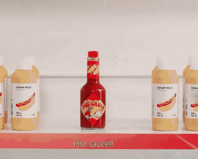 a person holding a bottle of hot sauce next to a bottle of senapp mild